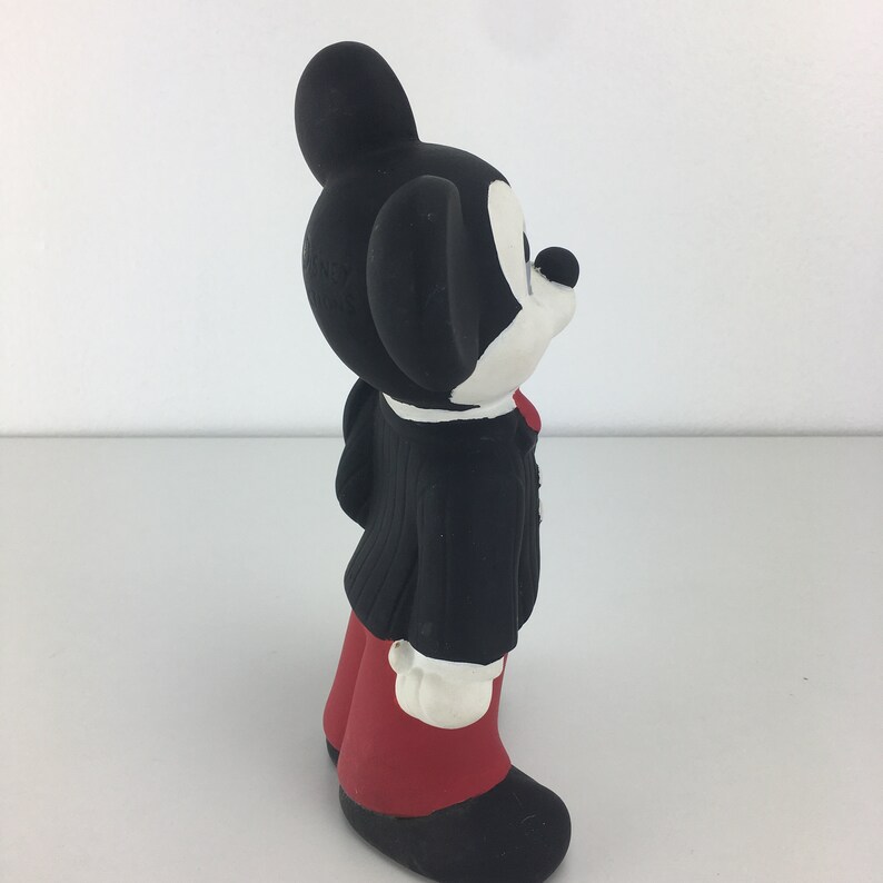 Op de afbeelding: Een zwart-witte keramische figuur van Mickey Mouse die een zwart pak en een rode broek draagt. Hij staat met zijn hoofd schuin.