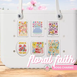 May include: White tote bag with floral-themed charms. The charms feature colorful flower arrangements and inspirational phrases like "Forgiven," "Forever," and "Grateful." The text "floral faith" and "Bogg Charms" are also visible.