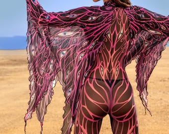 Può includere: Un body nero e rosa fantasia con maniche trasparenti abbinate. Il design presenta una rete di linee rosa e forme simili a occhi. La modella è in piedi in un paesaggio desertico con le braccia tese.