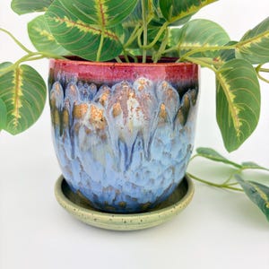 Handgemaakte keramische plantenpot in blauw en roze met drainagegaten en schotel. Gemaakt van gespikkeld aardewerk.