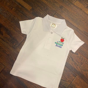Back to school white boys polo machine embroidered with either name or monogram below books with red apple on top