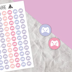 May include: A sheet of stickers with a variety of pastel colored circles featuring a white gamepad icon. The sheet has the word "ARRE" at the top. Two individual stickers are shown separately, one in a light purple color and one in a light pink color.