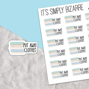 May include: A sheet of stickers with the text "It's Simply Bizarre" and multiple stickers with the text "Put Away Clothes". The stickers feature a stack of folded clothes in a blue, beige, and white color scheme.