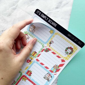 May include: Sheet of Christmas cat gift tags with various designs, including a cat in a wreath, a cat with a present, and a cat in a Santa hat. The tags have a white background with colorful borders and the text "It's Simply Bizarre" and "Xmas Cat Gift Tags".