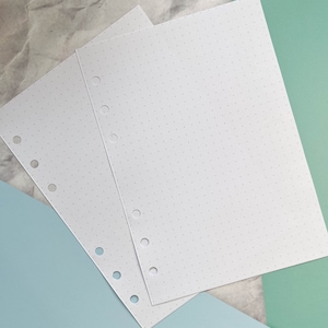 May include: Three white sheets of paper with evenly spaced holes along the left edge. The paper has a subtle dotted pattern.