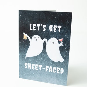 May include: A greeting card with a black starry night background featuring two white ghosts with happy faces. The ghosts are holding drinks and the text "Let's get sheet-faced" is written in white.