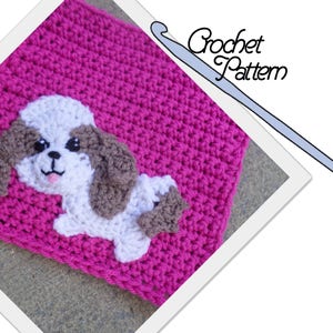 May include: A crochet pattern for a pink square with a white and brown Shih Tzu dog applique. The pattern includes a crochet hook.