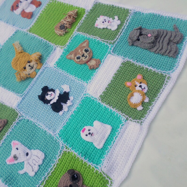 Pode incluir: Um cobertor de beb&eacute; de croch&ecirc; com um design de patchwork que apresenta v&aacute;rias ra&ccedil;as de c&atilde;es. O cobertor &eacute; feito com fio branco, verde e azul. Cada quadrado apresenta uma ra&ccedil;a de c&atilde;o diferente, incluindo um corgi, um pug, um poodle e um golden retriever.