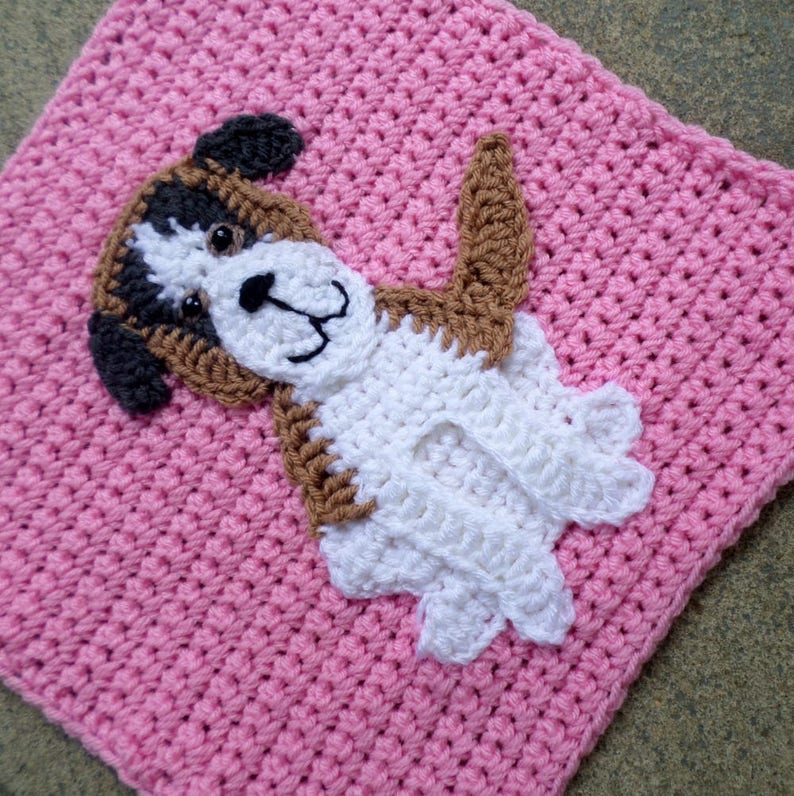 Peut inclure: Un carr&eacute; en crochet rose avec une applique de chien en crochet blanc, marron et noir au centre.