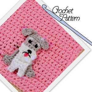 May include: A crochet pattern for a small gray and white dog with a pink nose. The dog is sitting on a pink crochet blanket. The image includes a crochet hook.