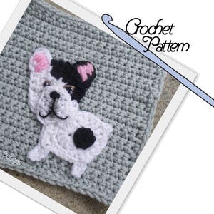 May include: Crochet pattern for a French Bulldog. The pattern includes a grey square with a white French Bulldog applique. The dog has black ears, a black spot on its back, and pink nose and ears.