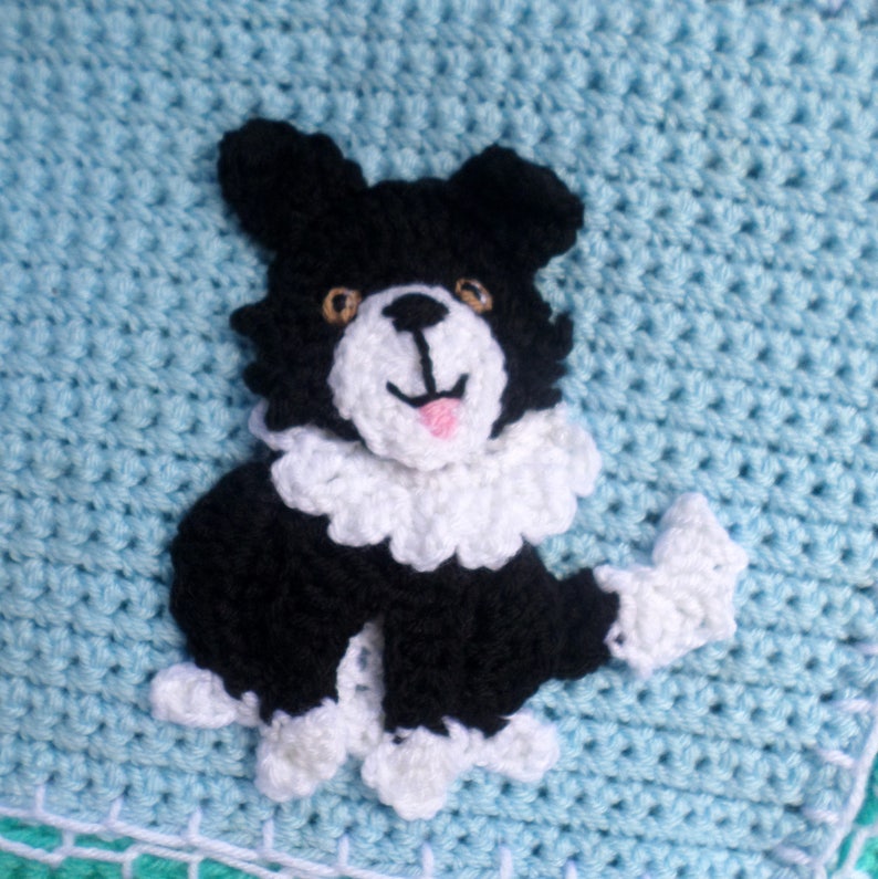 Puede incluir: Una aplicaci&oacute;n de perro de crochet negro y blanco con detalles blancos sobre un fondo de crochet azul claro.
