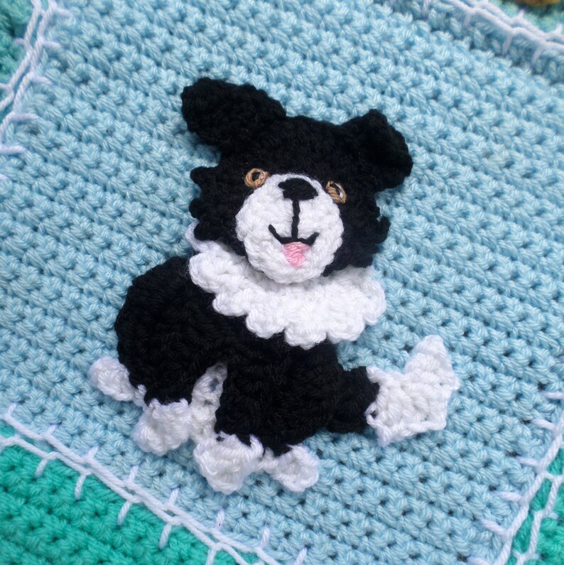 Puede incluir: Una aplicaci&oacute;n de perro de crochet en blanco y negro con un collar blanco y una lengua rosa claro. El perro est&aacute; sobre un fondo de crochet azul claro.