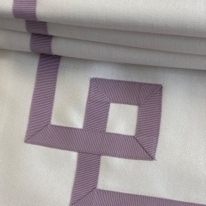 May include: White fabric with a geometric pattern of lavender ribbon trim. The pattern is a series of squares and rectangles.