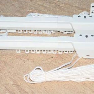 May include: White curtain track system with a pull cord. The track is made of a durable material and features small hooks for attaching curtains. The pull cord is white and coiled. The system is designed for easy installation and use.