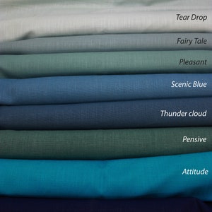 May include: A stack of eight fabric swatches in various shades of blue and green, with names for each color written below them: Tear Drop, Fairy Tale, Pleasant, Scenic Blue, Thunder Cloud, Pensive, Attitude, and Flattery.