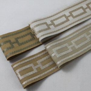 May include: Two fabric trims with a geometric pattern. One trim is green with a white pattern, the other is beige with a white pattern.