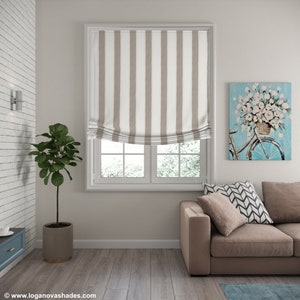 K&ouml;nnte beinhalten: Ein braunes und wei&szlig; gestreiftes Rollo mit wei&szlig;em Besatz, das an einem Fenster mit Blick auf eine verschneite Landschaft h&auml;ngt. Das Rollo ist hochgezogen und gibt den Blick auf das Fenster dahinter frei.