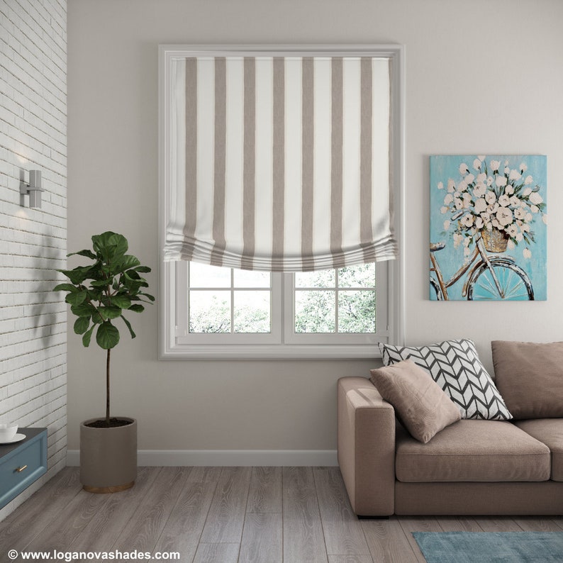 K&ouml;nnte beinhalten: Ein braunes und wei&szlig; gestreiftes Rollo mit wei&szlig;em Besatz, das an einem Fenster mit Blick auf eine verschneite Landschaft h&auml;ngt. Das Rollo ist hochgezogen und gibt den Blick auf das Fenster dahinter frei.