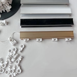 All four color options of the custom aluminum ripple fold curtain track - silver, white, black and gold rails with white snap carriers and pull cord, cut to any custom width
