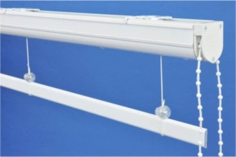 May include: White ceiling-mounted window blind system with a white metal track and white beaded chain.