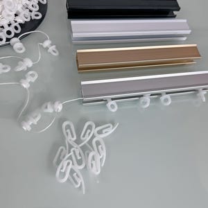 May include: Four different colours of curtain track, black, white, gold, and silver, with white plastic curtain rings.
