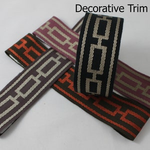 May include: Four rolls of decorative trim with a geometric pattern. The trim is available in black, brown, grey, and pink. The trim is labelled "Decorative Trim CE29".