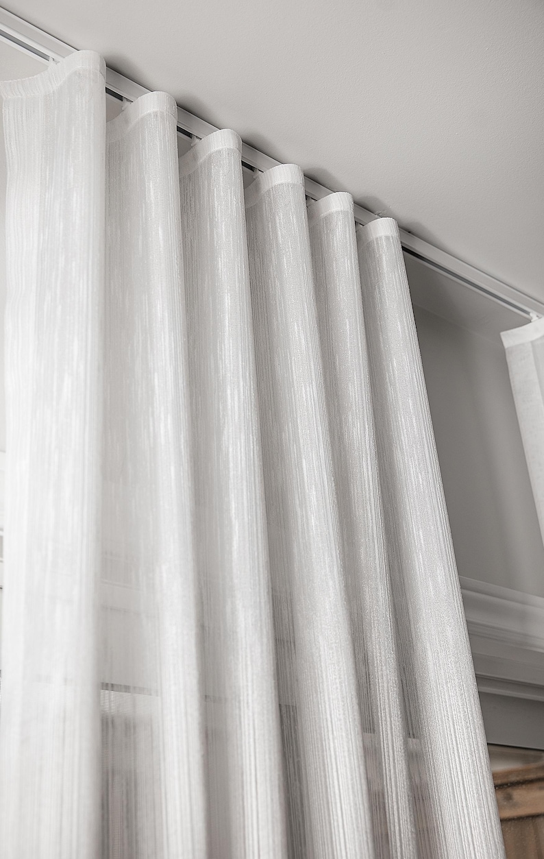Sheer white striped curtains draping in gentle s-fold waves from a ceiling-mounted ripple fold track - flush ceiling installation for a floating curtain look