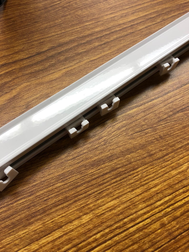 White aluminum ripple fold drapery track profile with snap carrier glides attached - close-up showing the slim low-profile design of the custom s-fold curtain rail