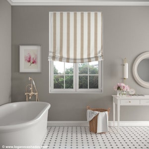K&ouml;nnte beinhalten: Ein Badezimmer mit einer wei&szlig;en Badewanne, einem wei&szlig;en Waschtisch mit Spiegel und einem Fenster mit einem beige-wei&szlig; gestreiften r&ouml;mischen Rollo. Der Boden ist mit schwarzen und wei&szlig;en Fliesen belegt.