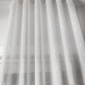 Sheer white curtains hanging in soft s-fold waves from a white ripple fold ceiling track - even ripple effect with 100 percent fullness created by evenly spaced snap carriers