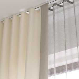Layered window treatment - cream wave fold drapery and gray sheer curtain hanging from two parallel ceiling-mounted ripple fold tracks for a double s-fold look