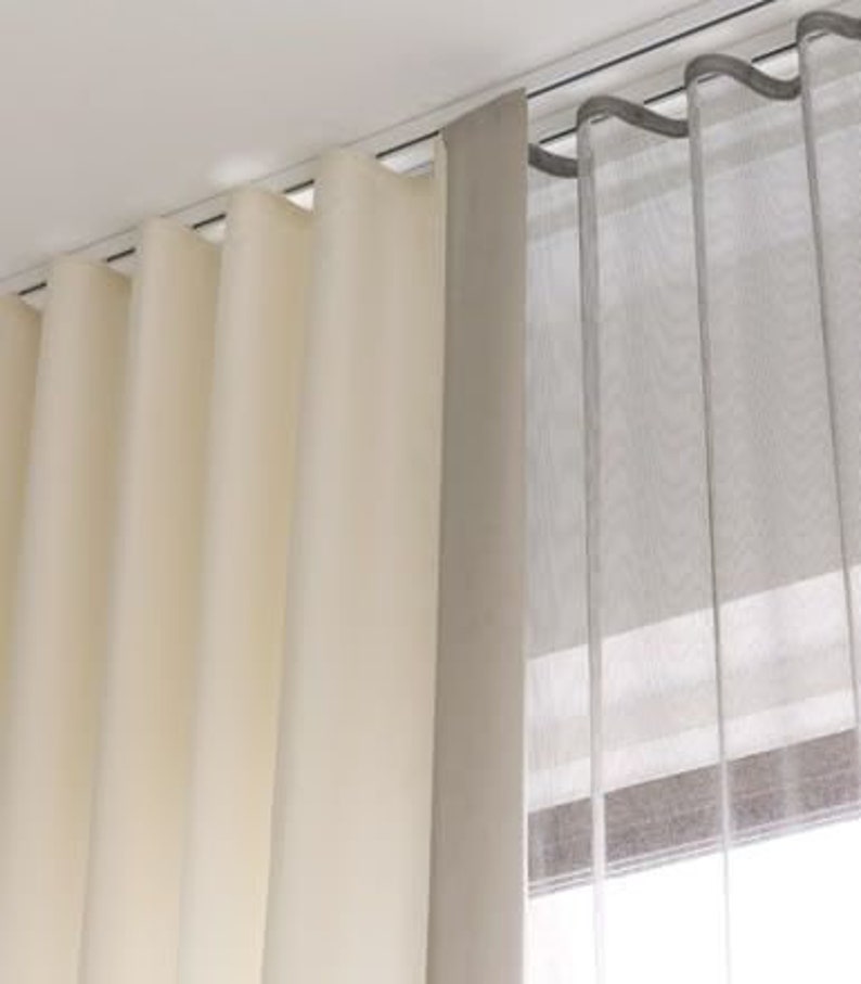 Layered window treatment - cream wave fold drapery and gray sheer curtain hanging from two parallel ceiling-mounted ripple fold tracks for a double s-fold look
