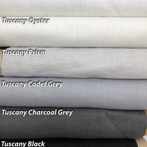 May include: Six rolls of fabric in various shades of gray, from white to black. The fabric is labeled from top to bottom: Tuscany White, Tuscany Oyster, Tuscany Prism, Tuscany Cadet Grey, Tuscany Charcoal Grey, and Tuscany Black.