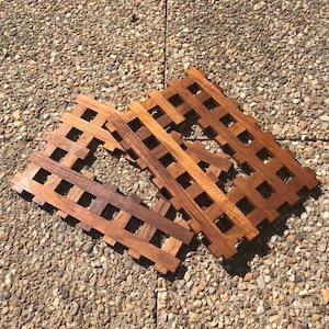 Puede incluir: Tres posavasos de madera con un patrón de rejilla. Los posavasos son de madera marrón claro y tienen un acabado natural.