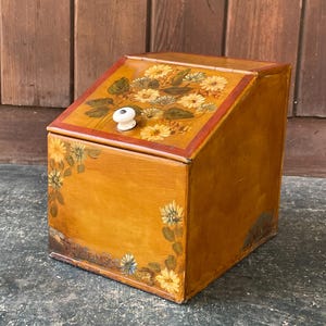 Panera de hojalata pintada con motivos florales, pomo de porcelana, caja inclinada, estilo vintage, antiguo, con flores ornamentadas, estilo rústico.