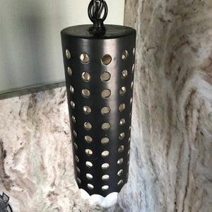 May include: Black metal pendant light fixture with a cylindrical shade featuring a pattern of evenly spaced circular cutouts.