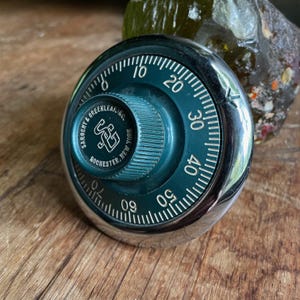 May include: A vintage combination lock with a green dial and chrome casing. The lock is labeled "Sargent & Greenleaf Inc. Rochester, New York".