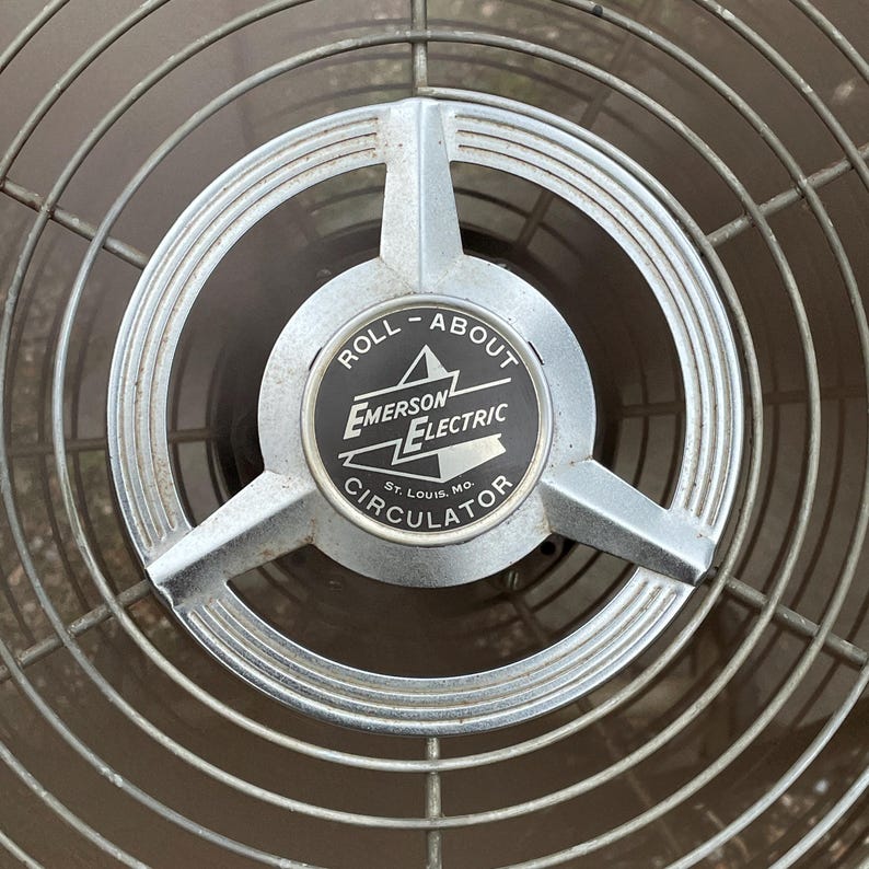 Peut inclure: Un ventilateur vintage argent&eacute; Emerson Electric Roll-About Circulator avec une &eacute;tiquette noire qui indique "Roll-About Emerson Electric St. Louis, Mo. Circulator".