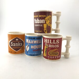 Könnte beinhalten: Vier Vintage-Kaffeetassen mit einzigartigen Designs. Eine Tasse zeigt "Yuban Coffee" mit einer Frau, die eine Tasse hält, eine andere "Sanka Coffee", eine dritte "Maxwell House Coffee" und die letzte "Hills Bros Coffee". Jede Tasse hat ein anderes Farbschema.
