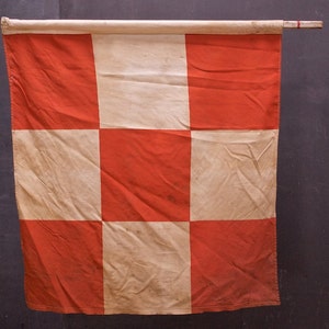 May include: A chequered flag with alternating red and white squares. The flag is made of fabric and has a slightly worn appearance.