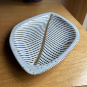 May include: White ceramic leaf-shaped dish with a raised, brown, leaf design.