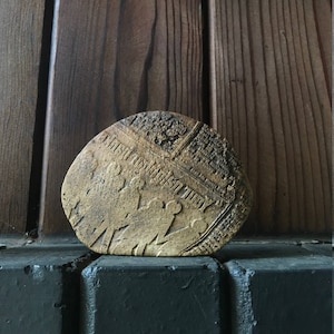 May include: A ceramic sculpture of a group of people walking, with a textured surface and a brown and gold color scheme.