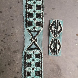 May include: A beaded belt and a smaller beaded piece. The belt features a teal suede backing with a geometric pattern of black and turquoise beads. The smaller piece has a similar design. The beads are arranged in a repeating pattern.