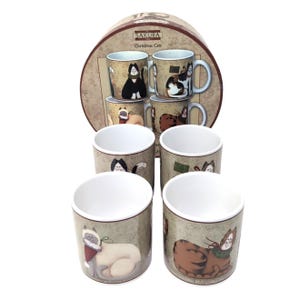 May include: A set of six ceramic mugs with cat illustrations, presented in a round box. The mugs feature various cat designs with holiday-themed accessories. The box is brown with the text "SAKURA Christmas Cats".