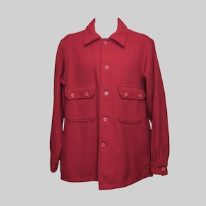 May include: A solid deep red long-sleeve shirt jacket featuring a pointed collar, a full-length front button closure, and two chest pockets with buttoned flaps. The garment has long sleeves with buttoned cuffs and a straight hemline design.