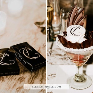 May include: Two black playing card boxes with the date 11.21.21 and the letter "L" in a decorative font. The boxes are on a wooden table. A chocolate dessert with a white chocolate topping with the letter "L" in a decorative font is in a martini glass on a white surface.