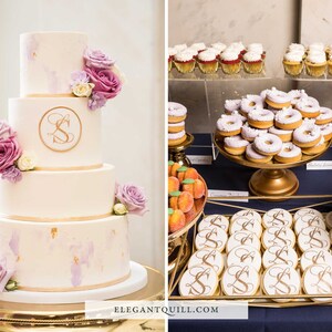 May include: A four-tier wedding cake decorated with purple and white flowers and gold accents. The cake has a monogram "S" on the second tier. The dessert table also features cupcakes, donuts, cookies, and peach-shaped treats.