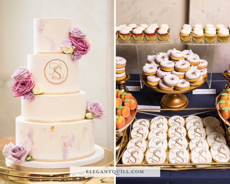 May include: A four-tier wedding cake decorated with purple and white flowers and gold accents. The cake has a monogram "S" on the second tier. The dessert table also features cupcakes, donuts, cookies, and peach-shaped treats.