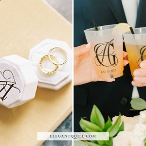 May include: Two white ring boxes with black calligraphy initials "AG" and the date "July 23, 2022". The boxes are open and contain two gold wedding bands. Two clear plastic cups with black calligraphy initials "AG" and the date "July 23, 2022" are filled with a light yellow beverage.